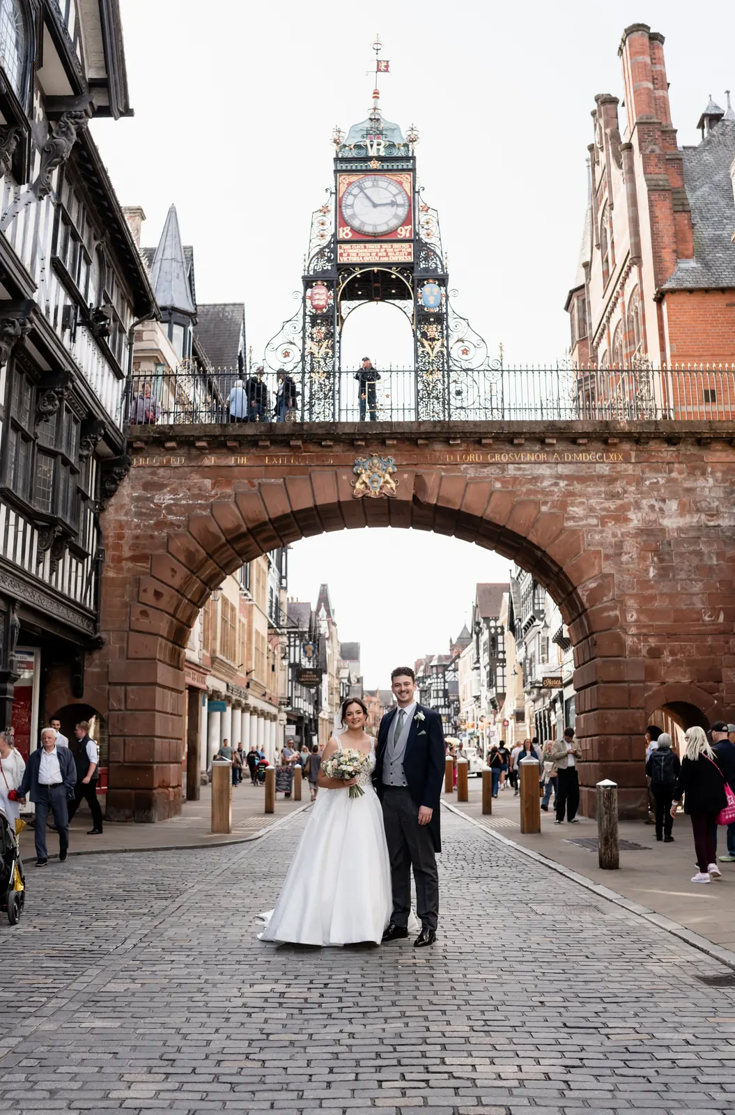 Bride and groom beneath the Eastgate Clock in Chester on their wedding day